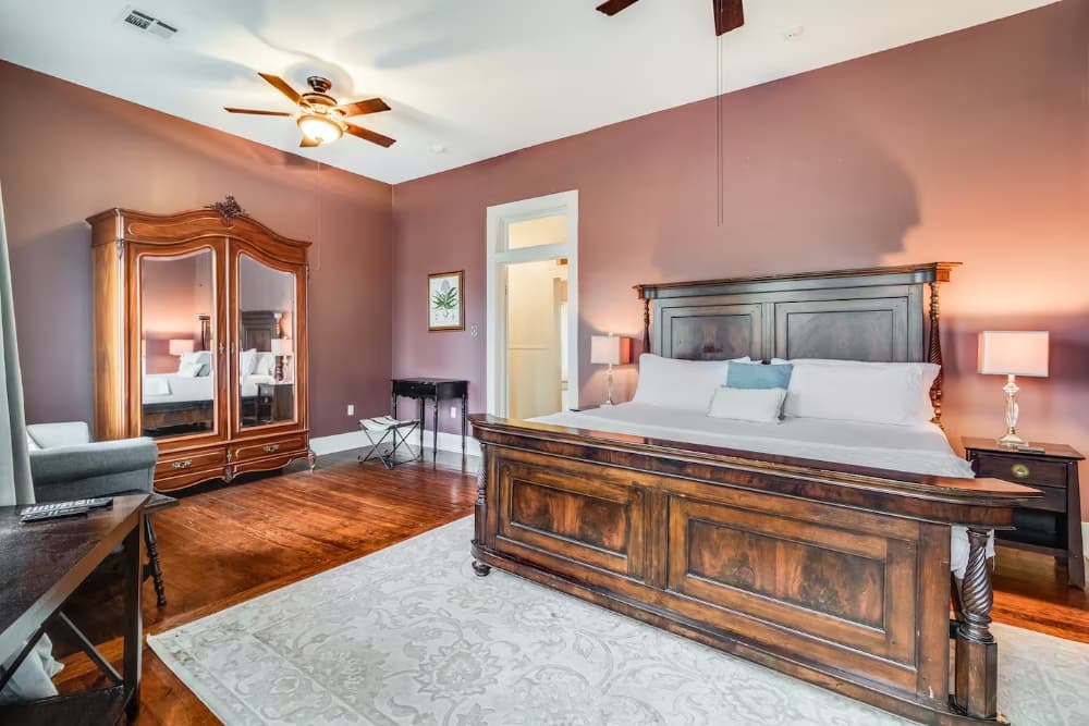 A cozy bedroom featuring a wooden bed frame, a large mirrored wardrobe, and warm wall colors.