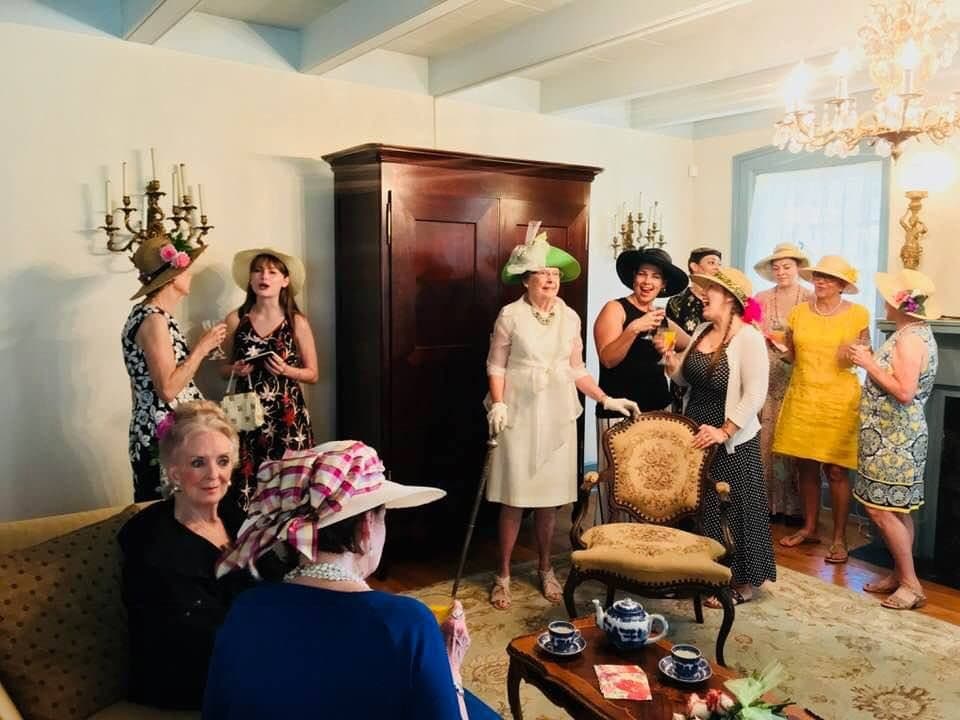 A lively gathering of women in fashionable hats enjoying conversation in a charming interior.