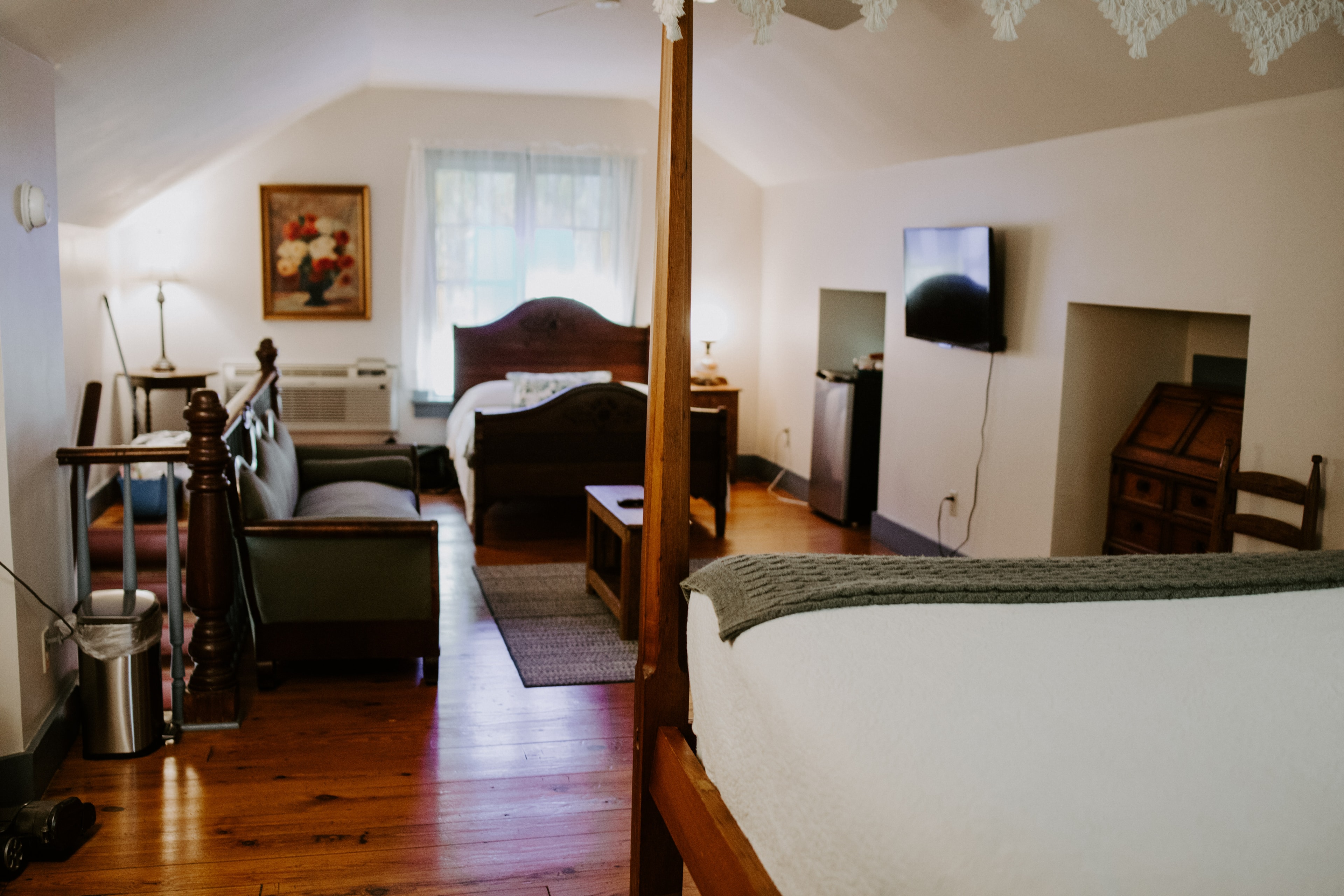 Cozy bedroom featuring two beds, a sitting area, and a TV in a warm, inviting space.