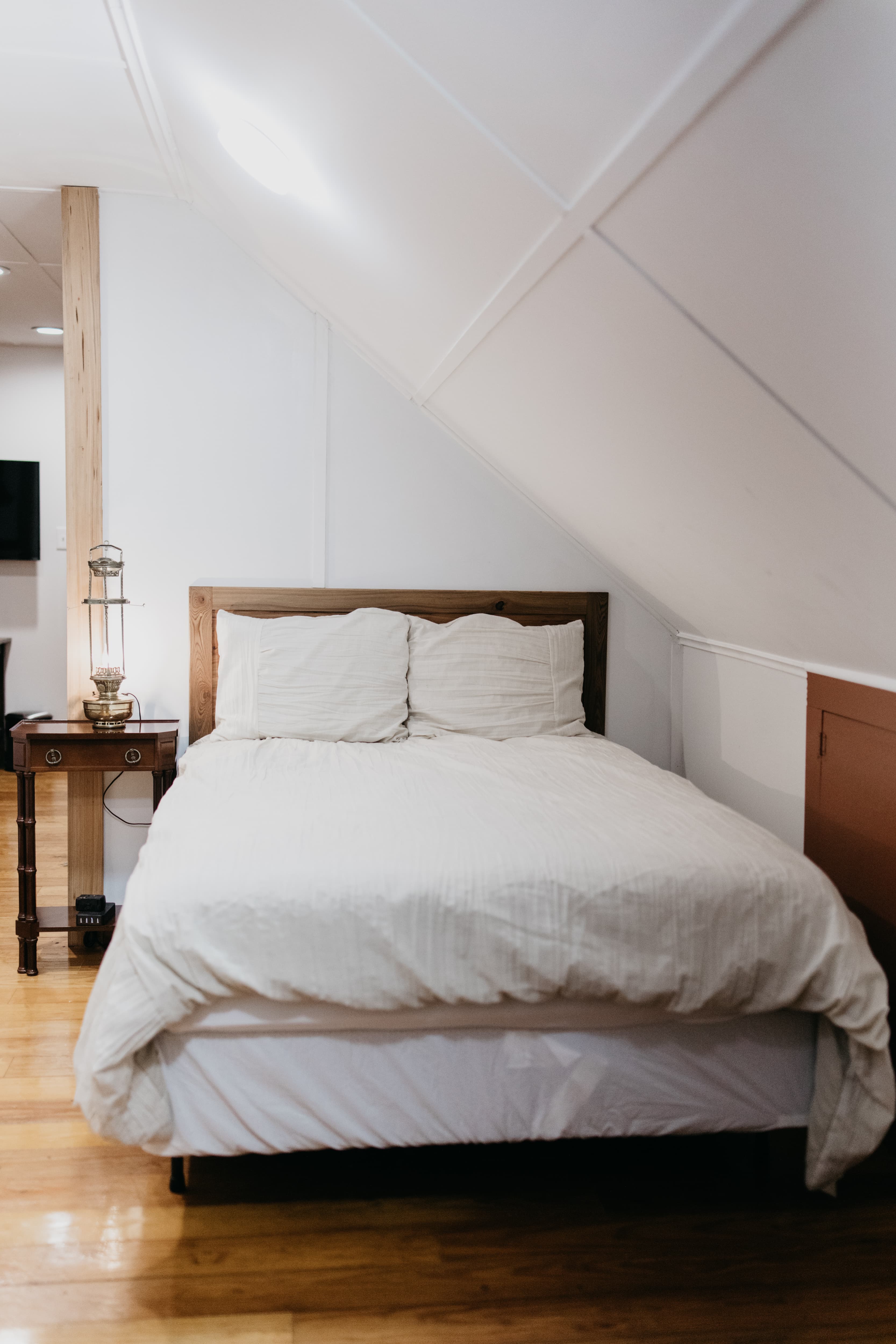 Cozy bedroom with a wooden bed, white bedding, and a bedside table.