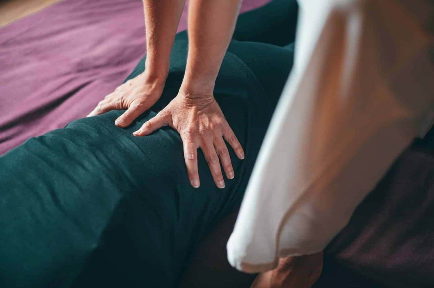A person's hands are applying pressure on a person's back during a massage.