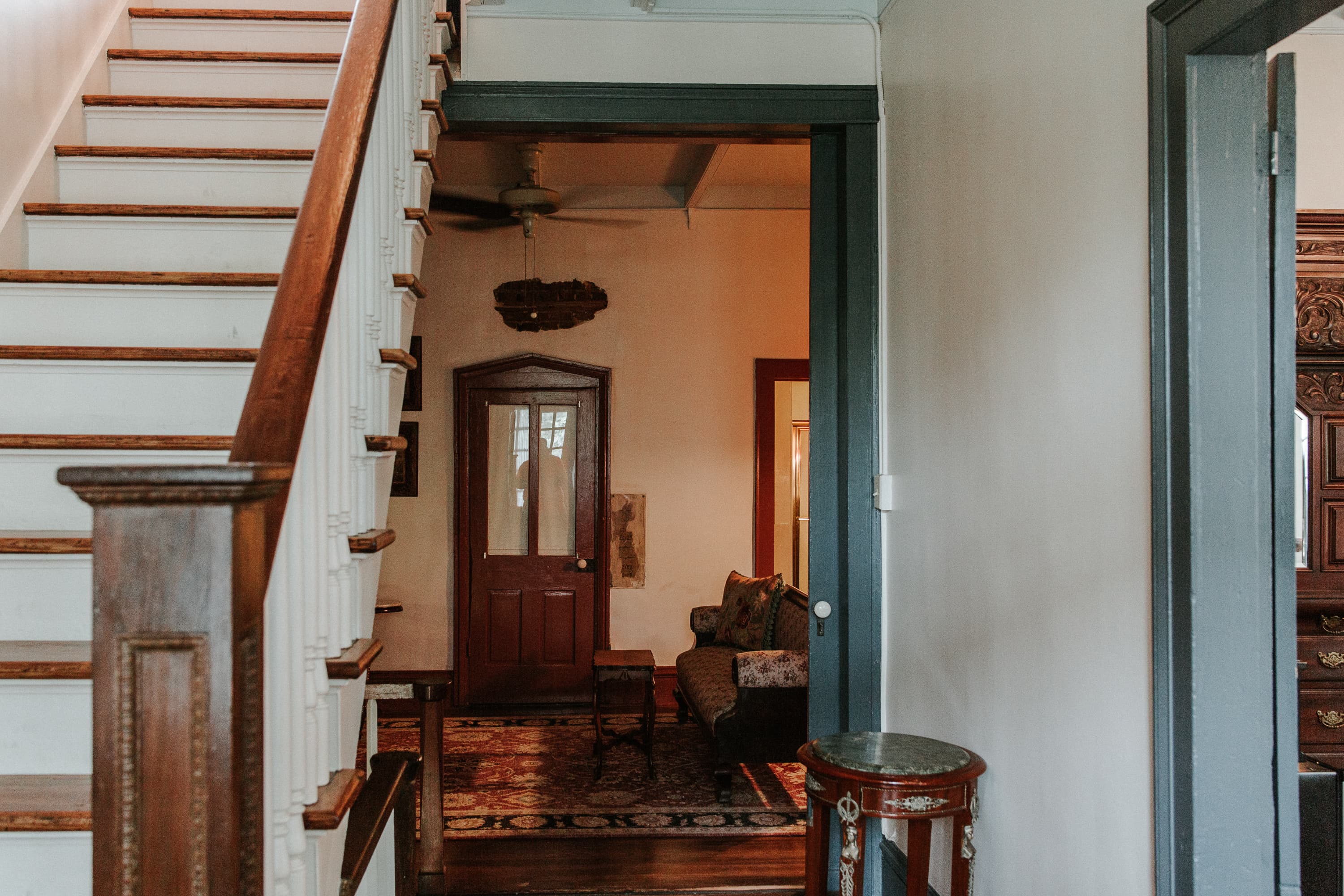 A glimpse of a welcoming entryway featuring a staircase and a cozy sitting area beyond an open doorway.