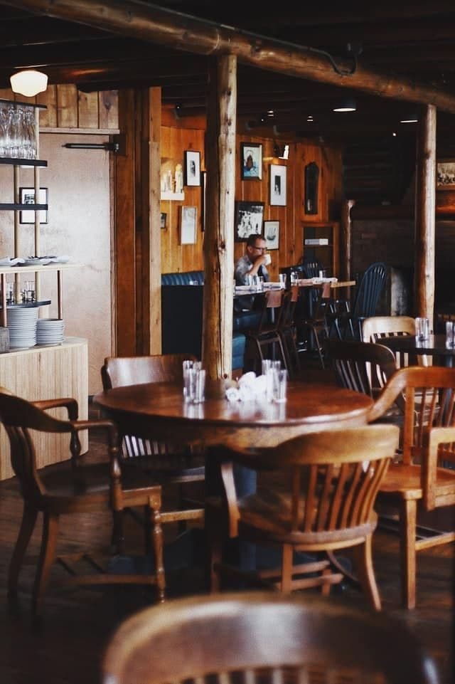 A cozy restaurant interior with wooden decor and a solitary diner at a table.