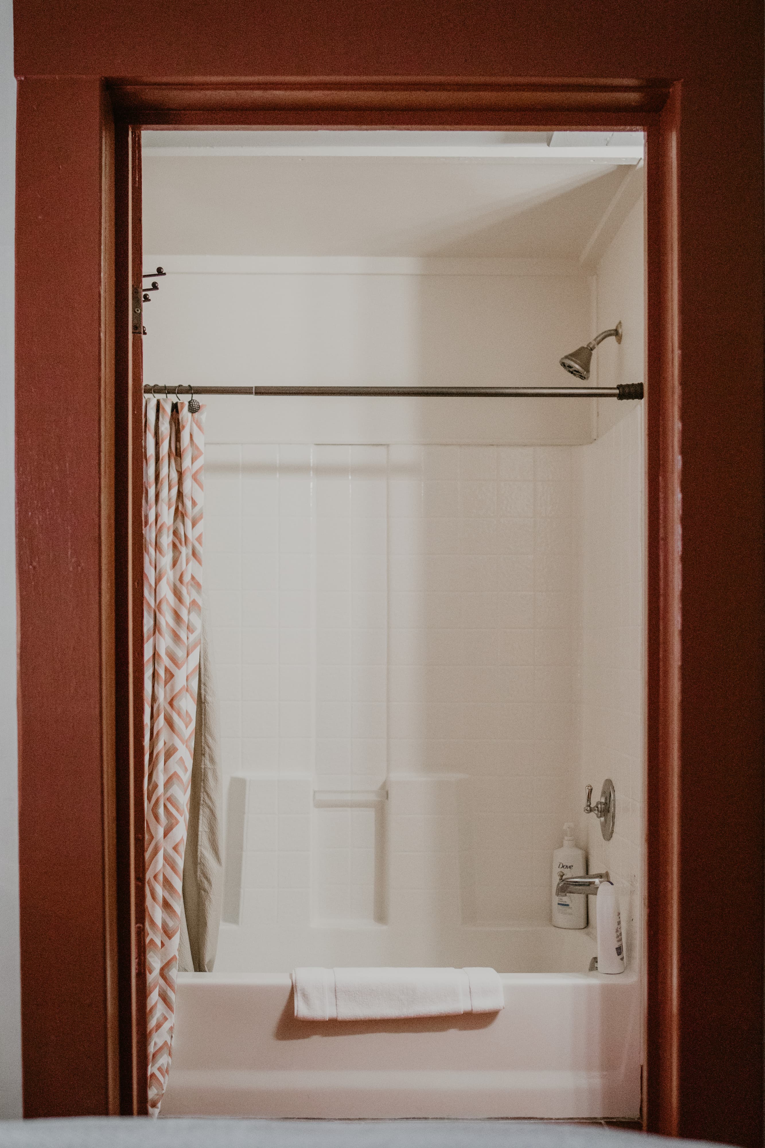 A view of a bathroom with a shower and bath tub framed by a red door.