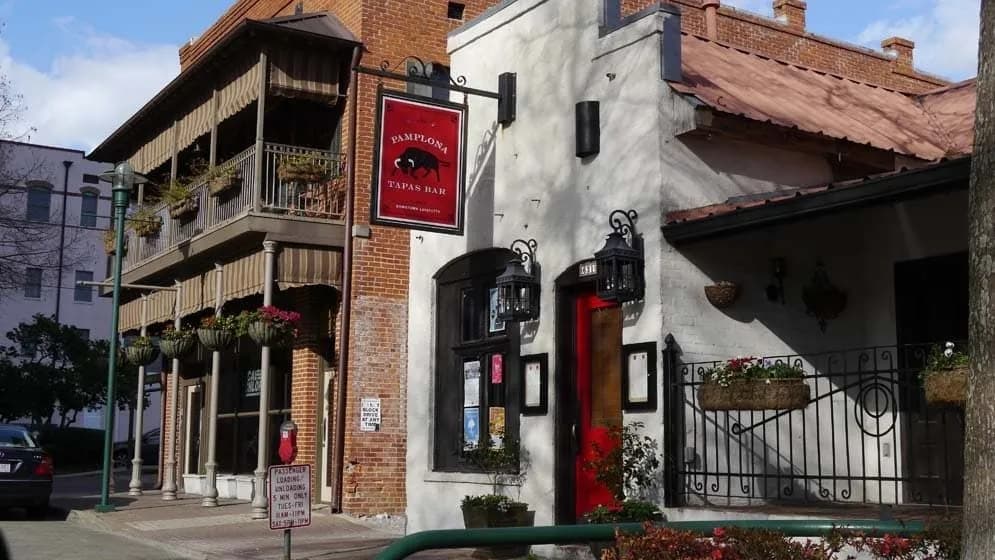 Exterior view of a tapas bar featuring a red sign and charming architectural details.
