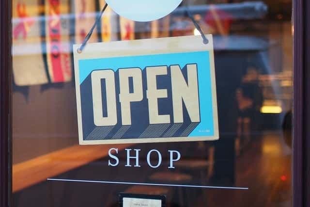 A blue and yellow "OPEN" sign hangs in the window of a shop.